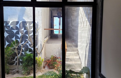 Chuburna Puerto Cottage | Pasilla suite. Ocean view glass doors to the turquoise water, 13foot Tv screen