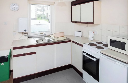 Chysauster Cottage | This bronze bungalow features an open kitchen, dining room, and living room.